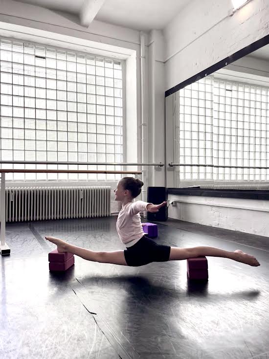 A young student practising the splits in the studio